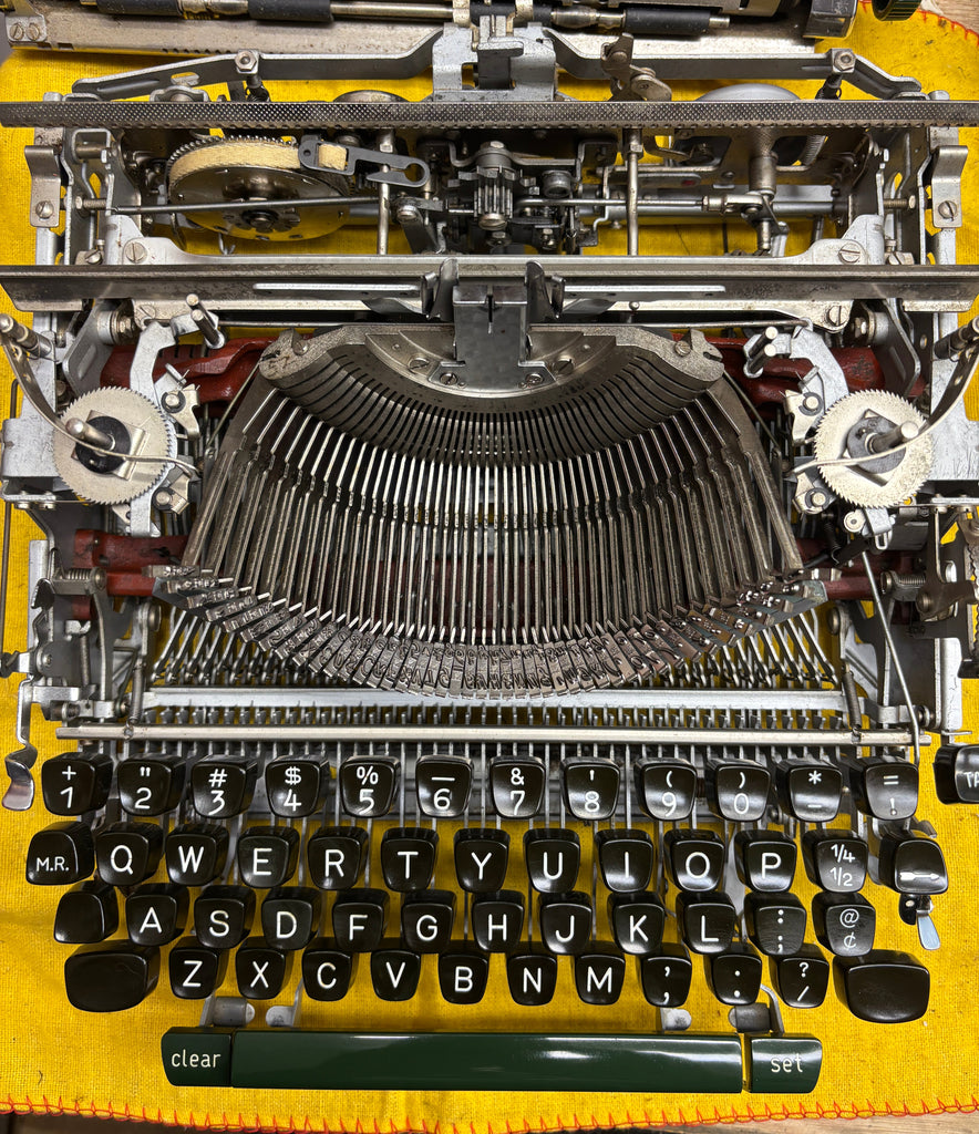 Close-up of an old Olympia SM4  typewriter with visible mechanical components on a yellow background