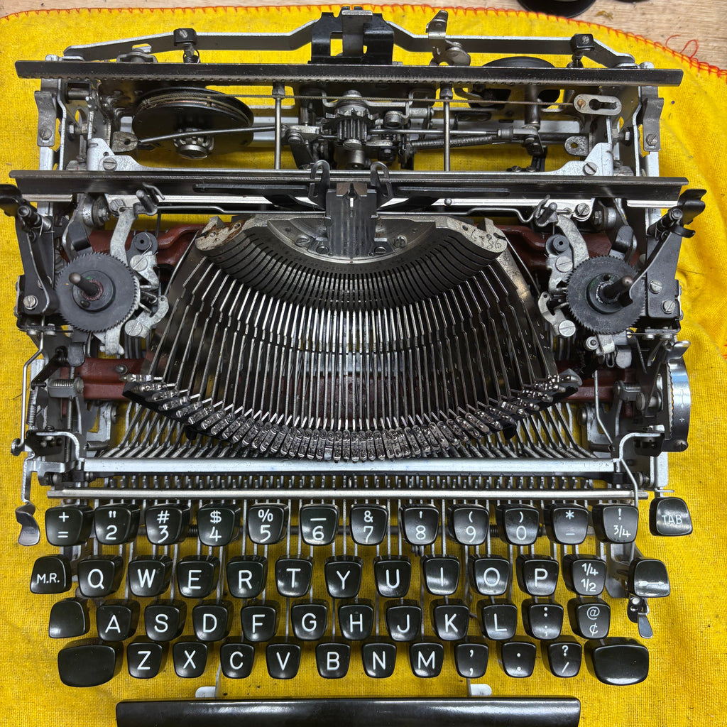 Disassembled vintage typewriter on a yellow surface